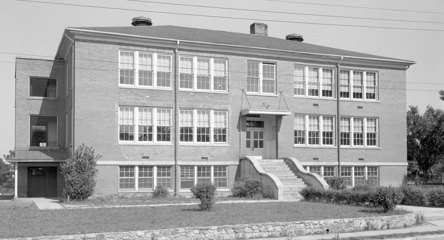 Old black and white photo of a 3 story brick schoolhouse.