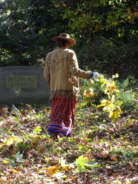Older volunteer carrying weeds out of Oberlin Cemetery.