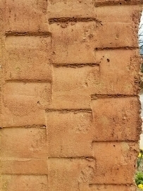 Closeup of texture of The Farmer pillar. A garden hoe was used to create a texture to represent farming which sustained the community, especially in its early days.